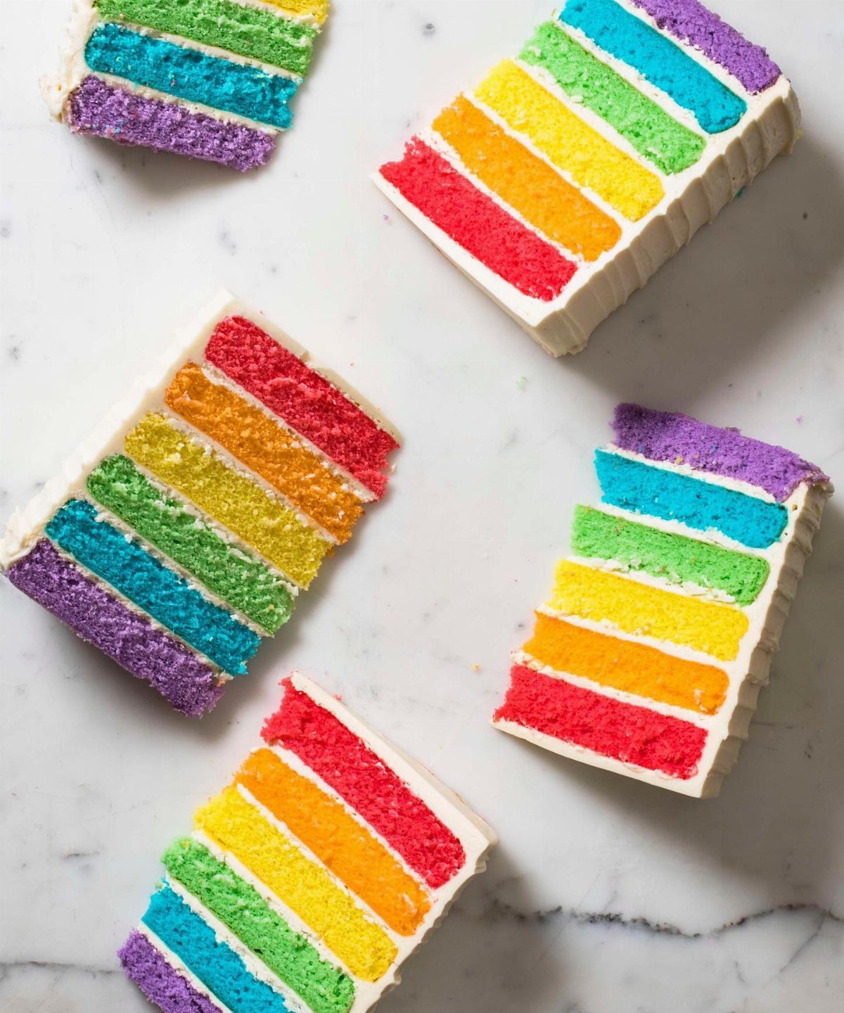 Rainbow layer cake with vibrant colored layers on a marble surface.