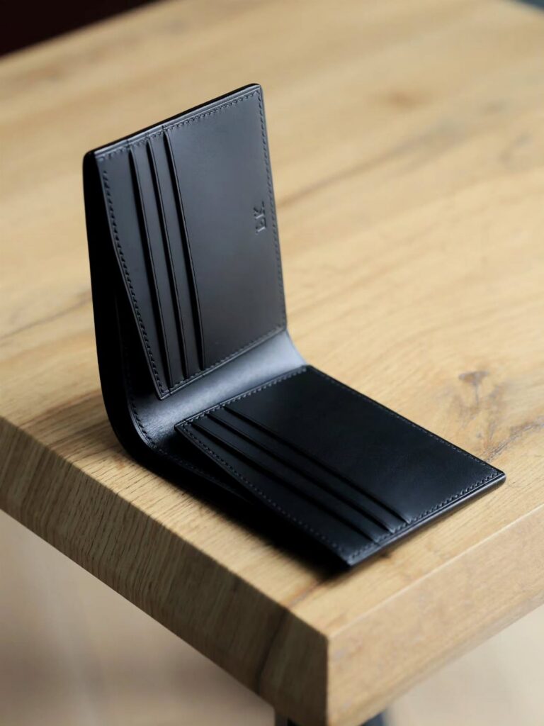 An open black leather bi-fold wallet resting on a light wooden tabletop.