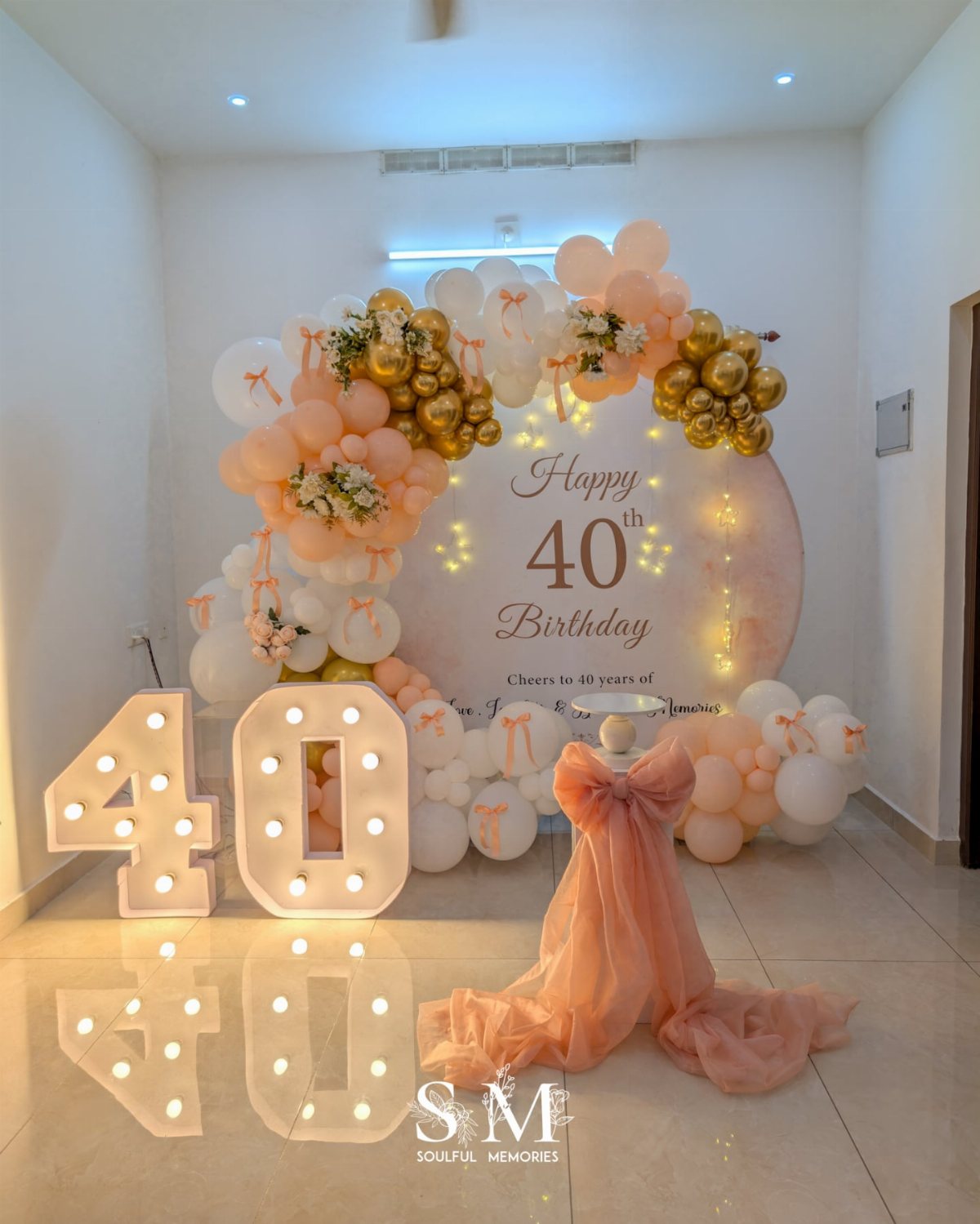 A 40th birthday decoration setup with peach balloons and large light-up numbers.