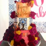 A three-tiered floral birthday cake featuring blue tile patterns and a gold number fifty.