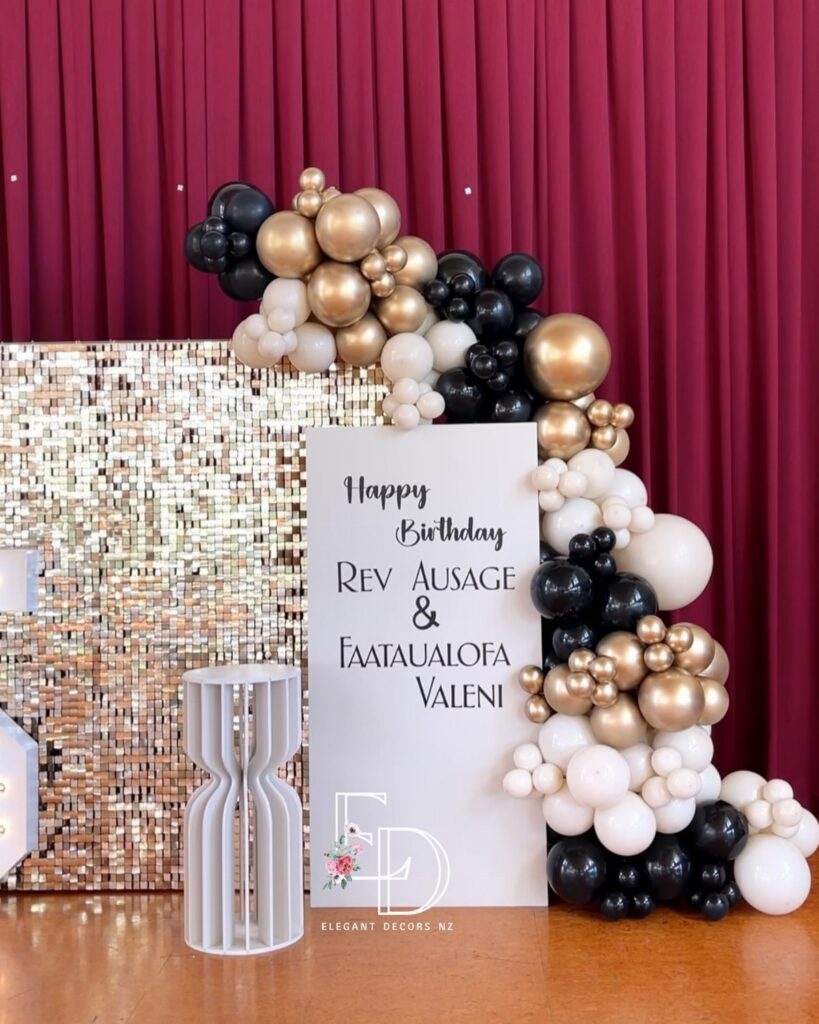Balloon garland in gold, black, and white decorating a birthday sign and sequin backdrop.