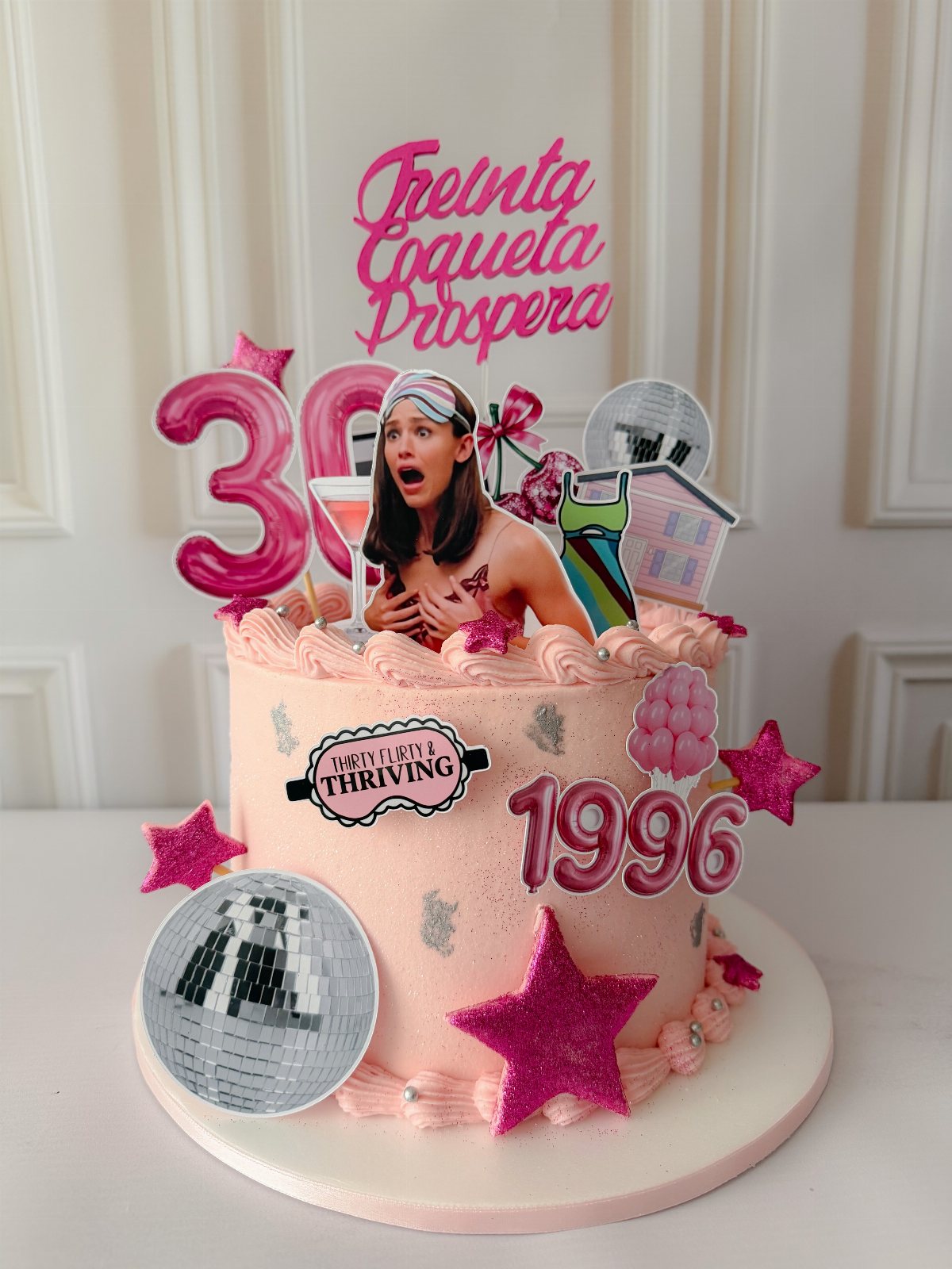 Pink decorated birthday cake with glittery stars, a disco ball, and a large number thirty topper.