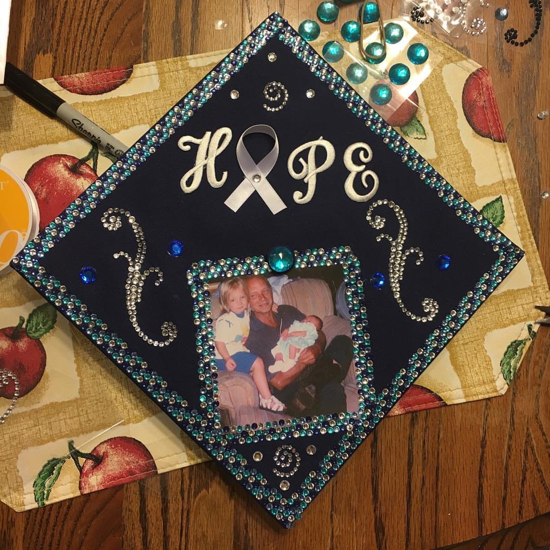 Decorated navy blue graduation cap with rhinestones, a photo, and the name HOPE.