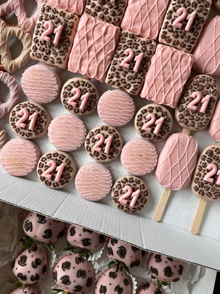 Pink and leopard print cookies, cake pops, and strawberries decorated with the number 21.