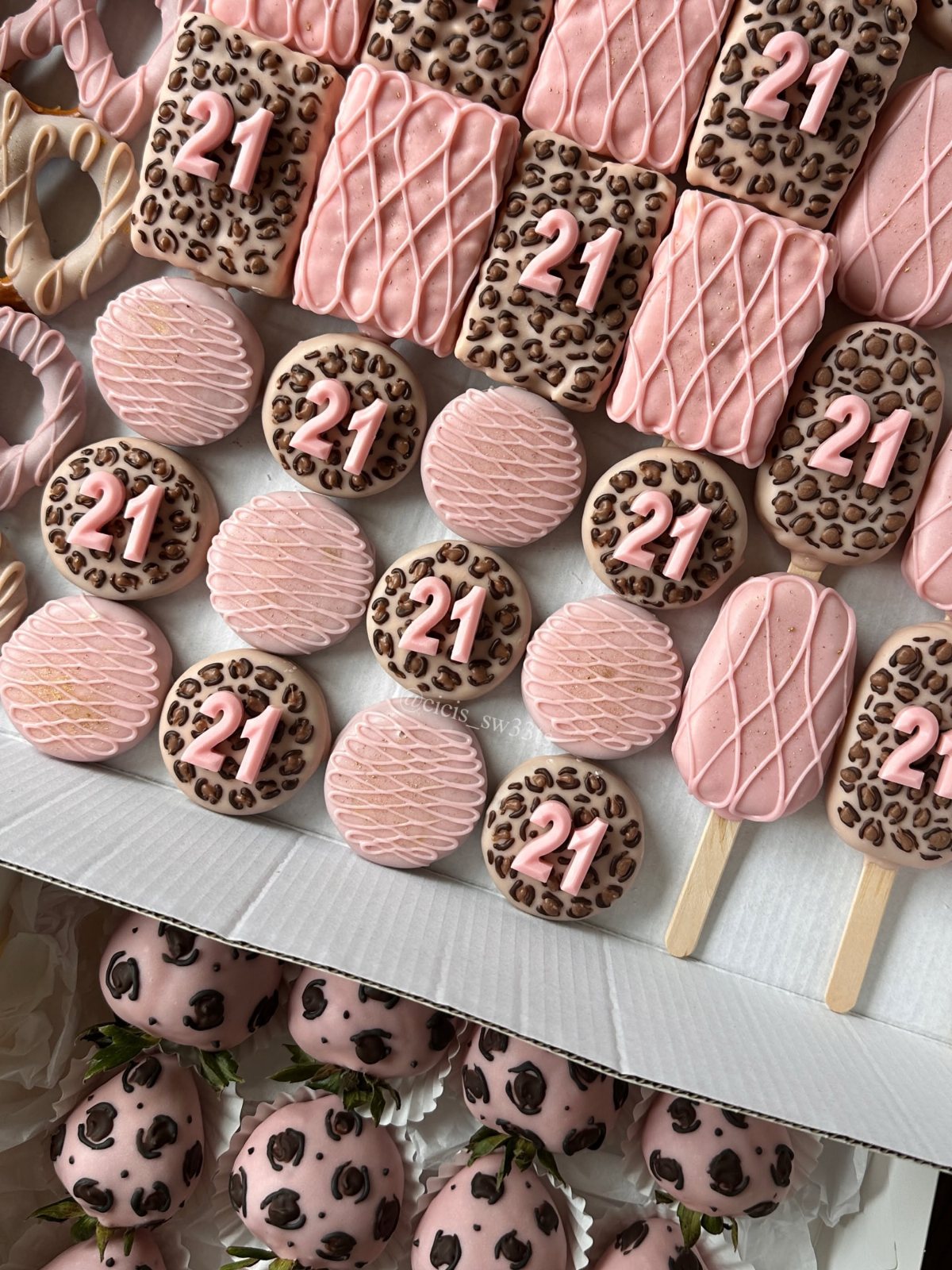 Pink and leopard print cookies, cake pops, and strawberries decorated with the number 21.