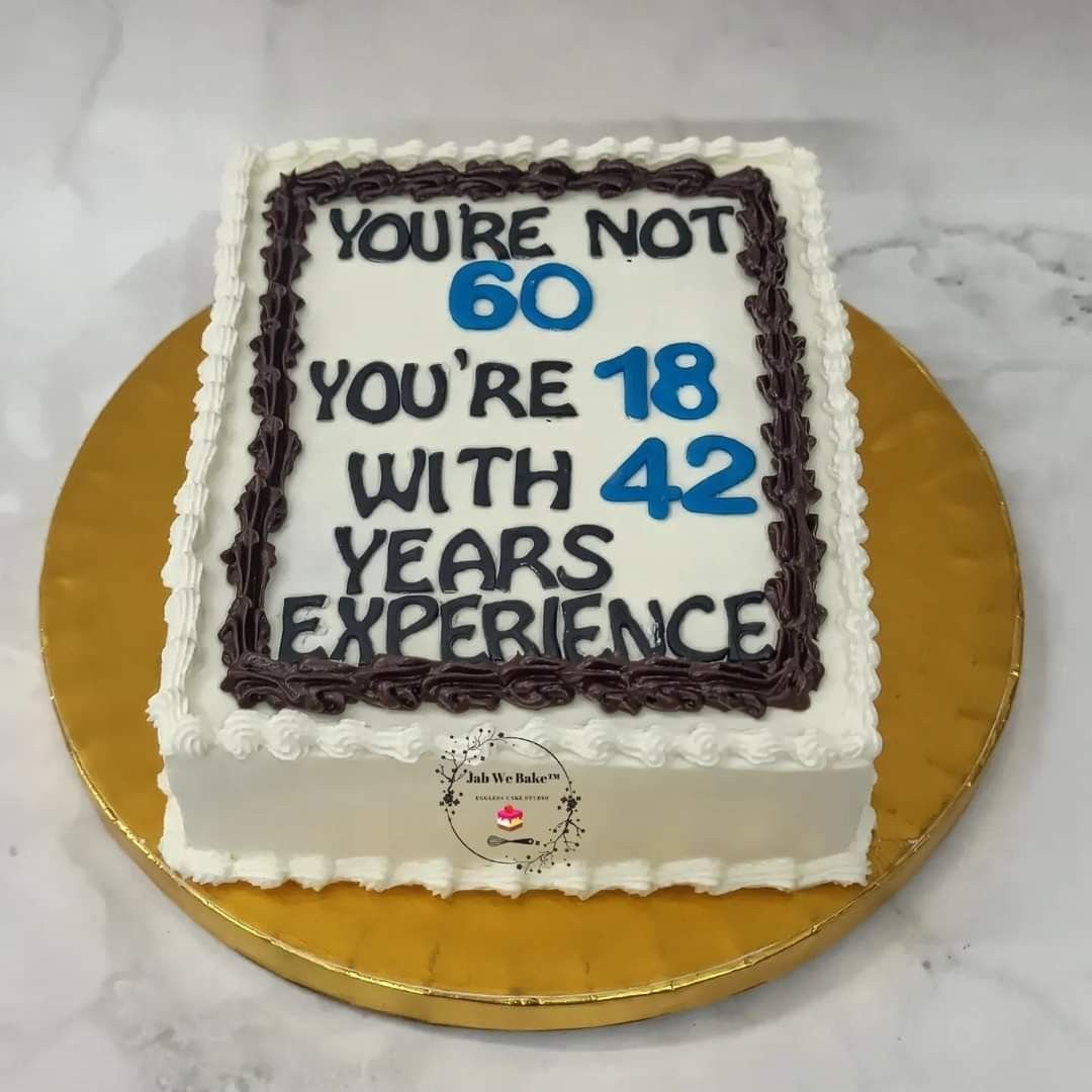 A rectangular white cake with blue text celebrating a 60th birthday on a gold platter.