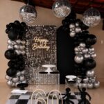 Disco balls and black and silver balloons decorate a 60th birthday party setup.